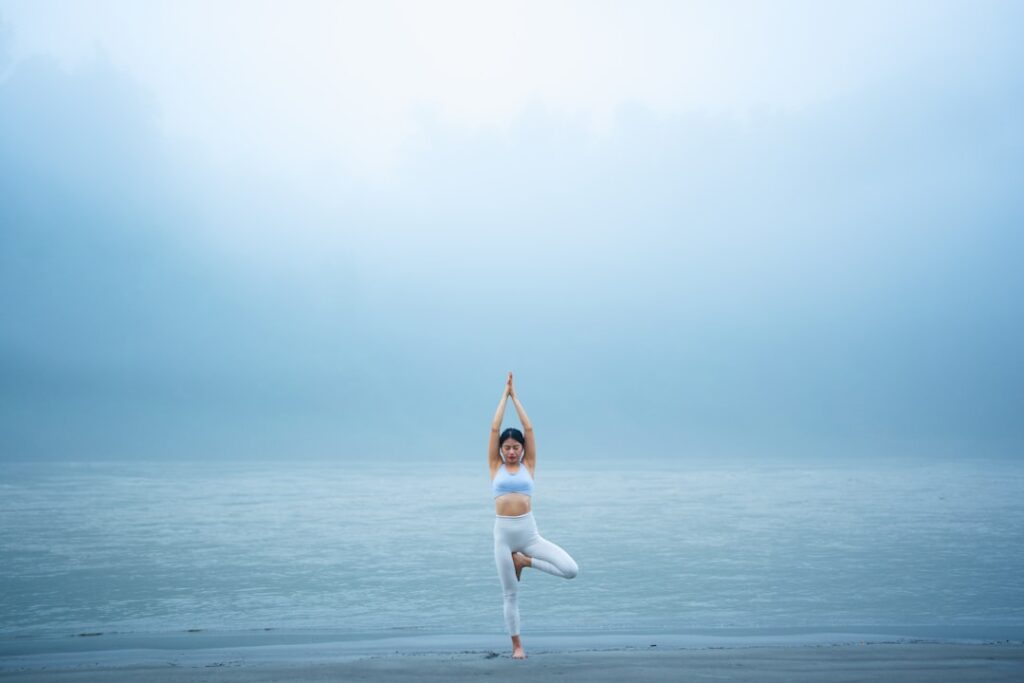 A woman standing on one leg on a beach