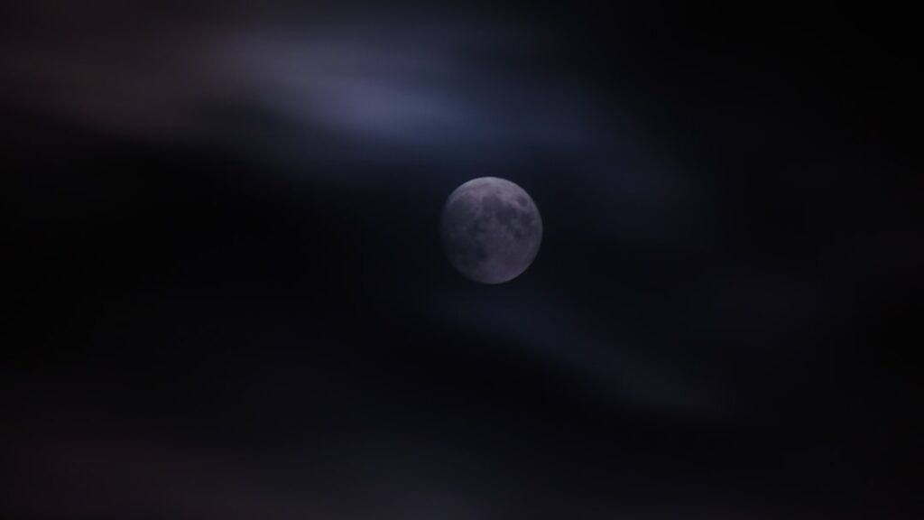 a full moon seen through the clouds in the night sky