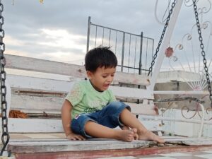 a young boy sitting on a porch swing